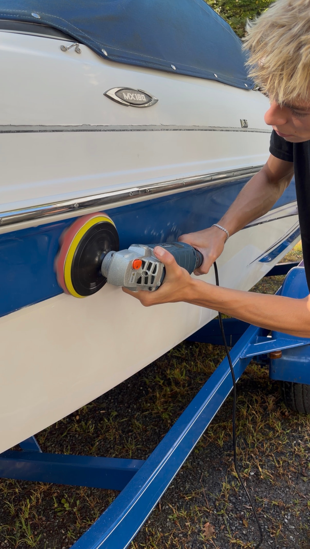 Machine polishing the blue hull of a Glastron boat